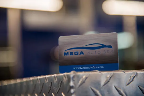 A MEGA Auto Spa membership card resting on a diamond-plate counter